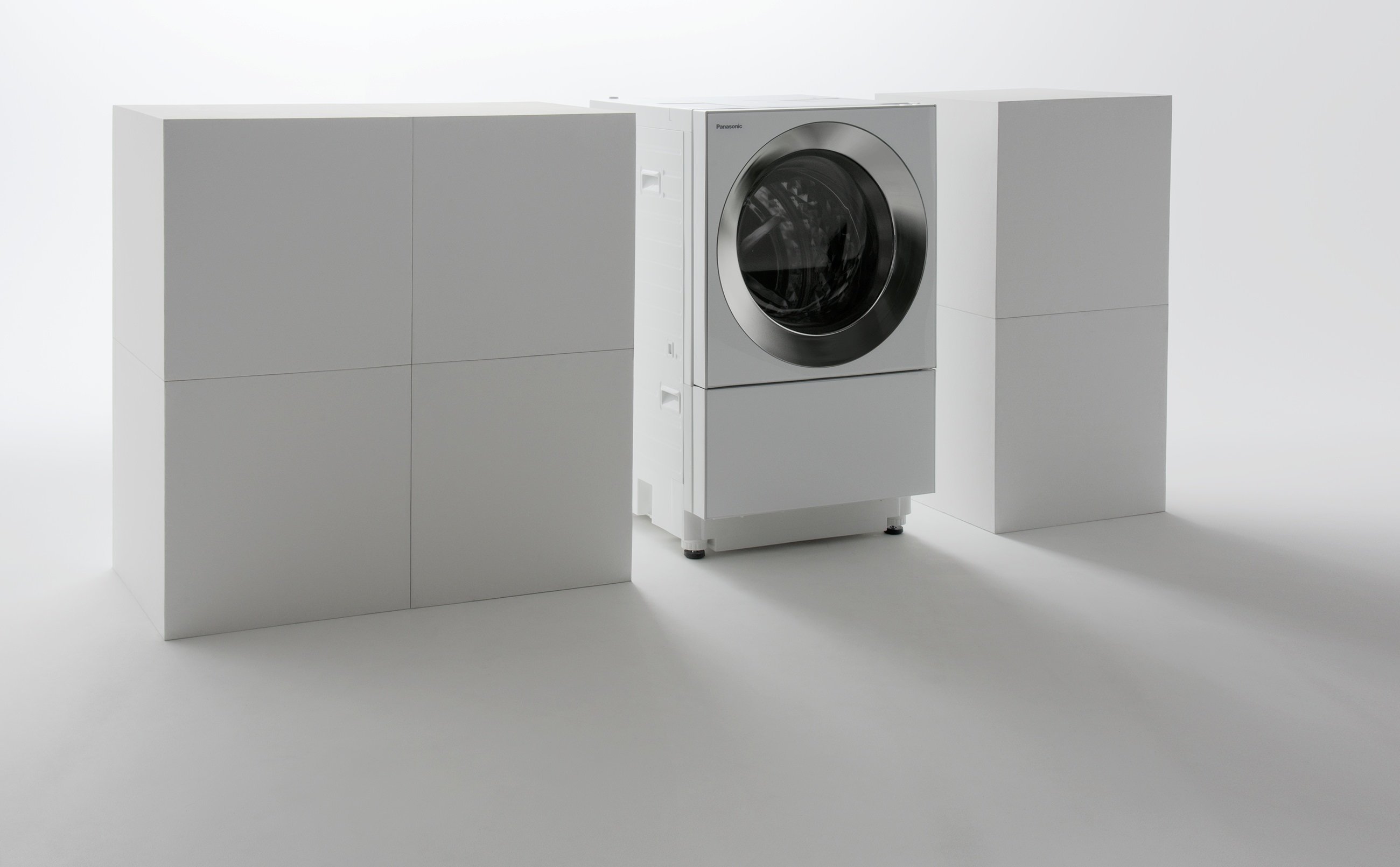 Tilted-drum washing machine between white cabinets.