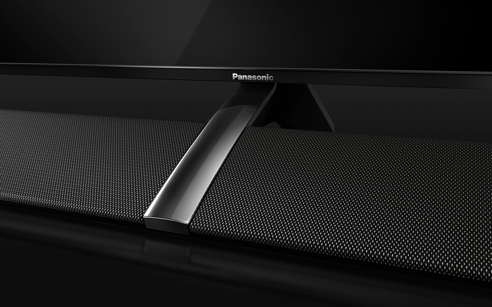 A close-up of a Panasonic speaker with a textured black surface and a metallic strip in the center, set against a dark background.