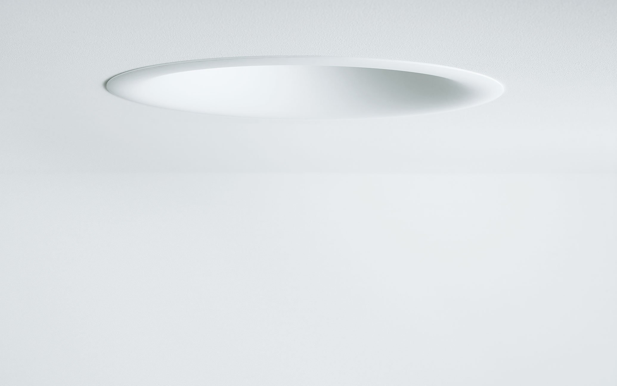 Close-up of an oval-shaped embedded LED ceiling light in a white ceiling