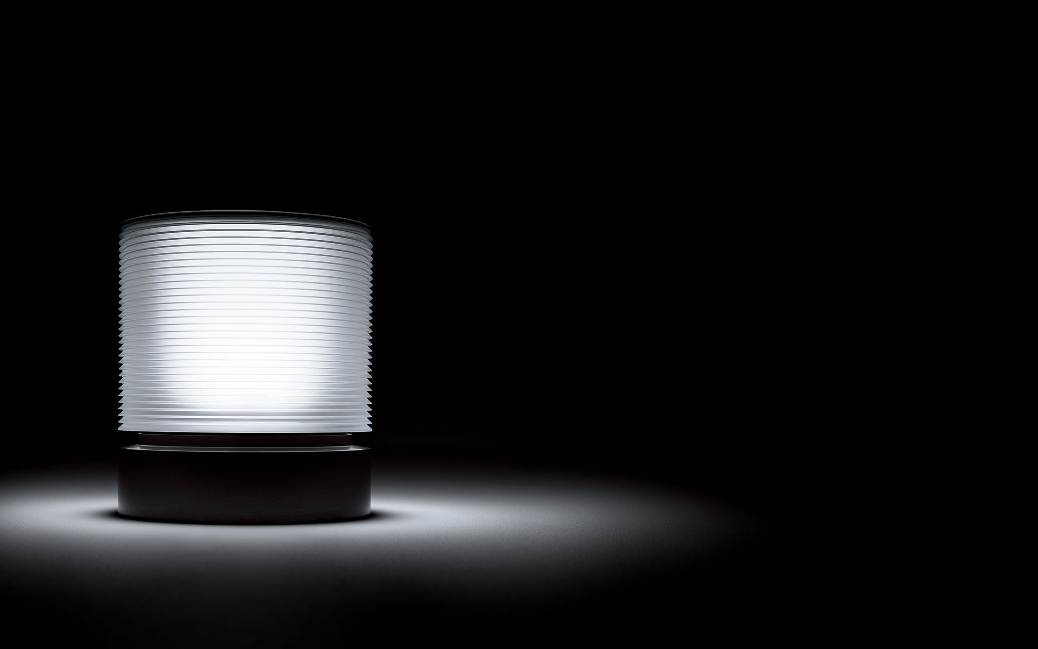 Close-up of a white cylindrical light fixture illuminated against a black background