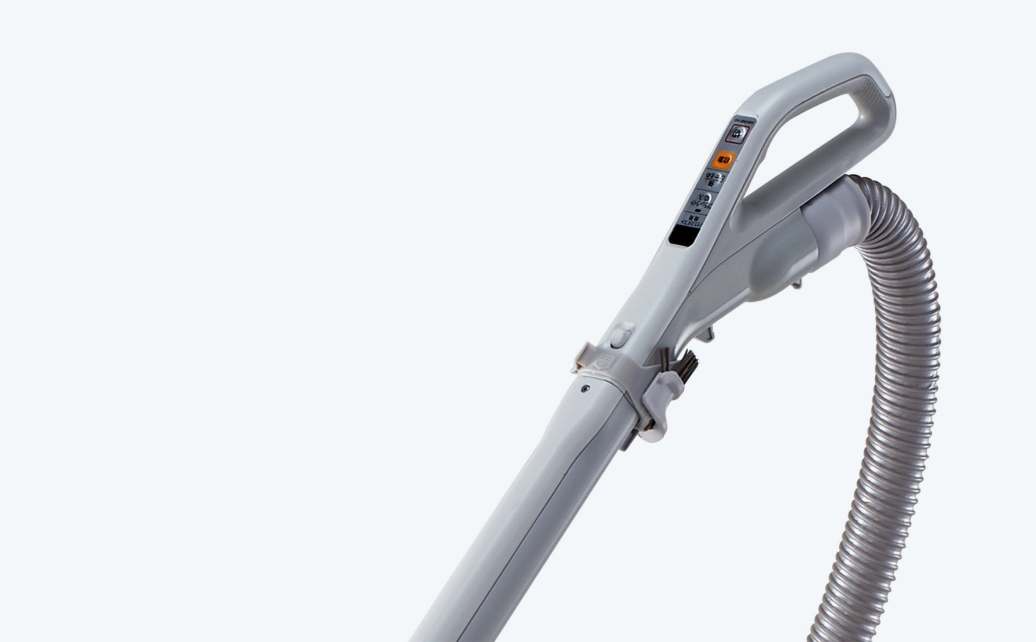 Close-up of a vacuum cleaner handle with control buttons and a flexible gray hose attached, set against a plain white background.