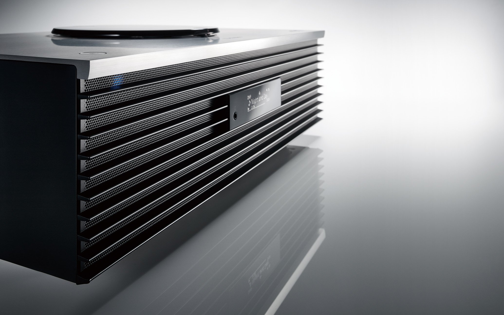 The design features a silver CD player mounted on top, with a black speaker front and a small display in the center.