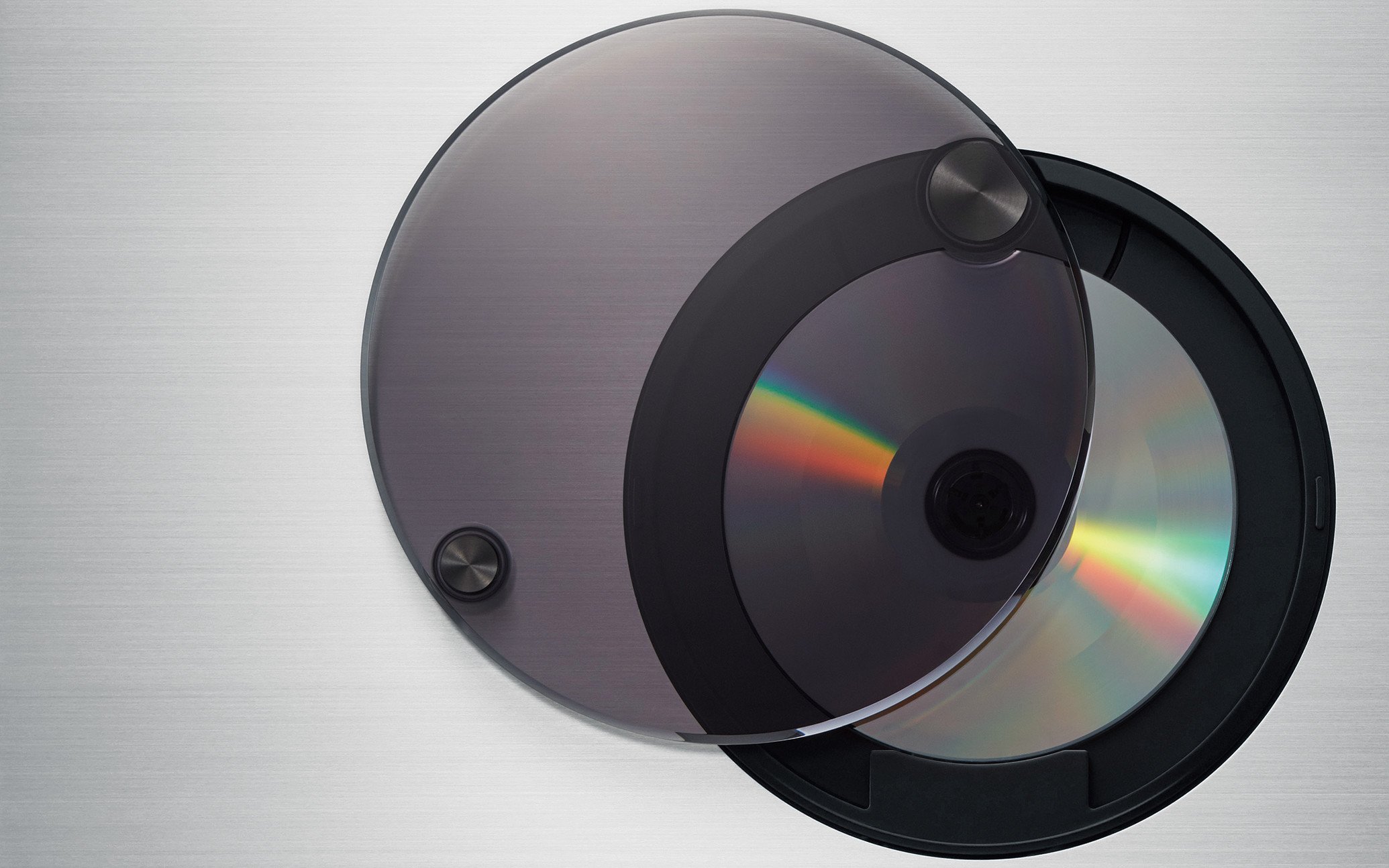 A gray circular disc covered with a transparent lid, placed on top of a CD player, with the disc's surface visible underneath.