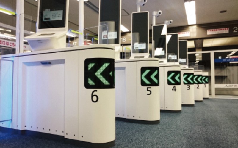 Airport check-in kiosks lined up in numerical order, each with display screens and cameras in front