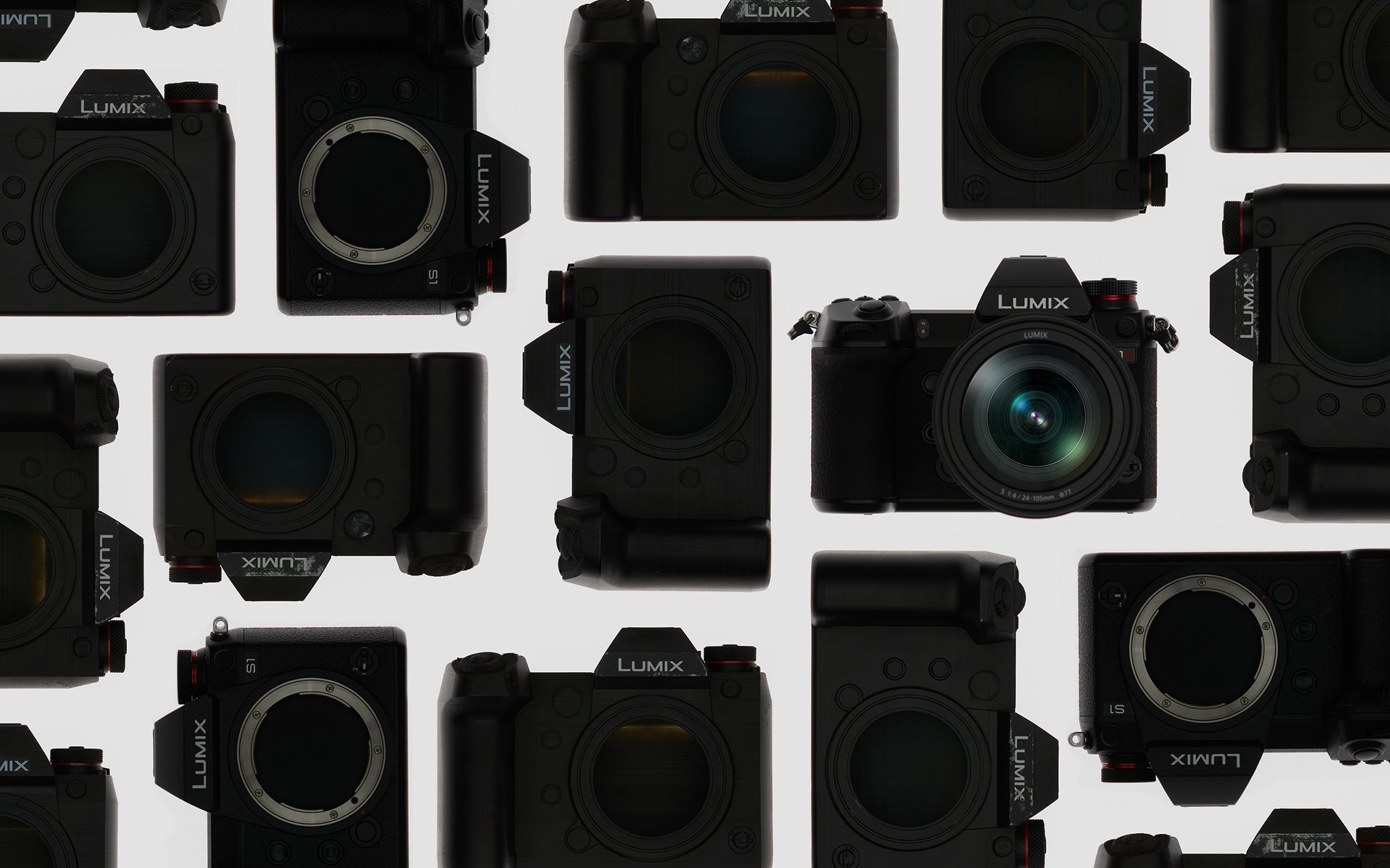 Multiple black mirrorless cameras arranged on a white background