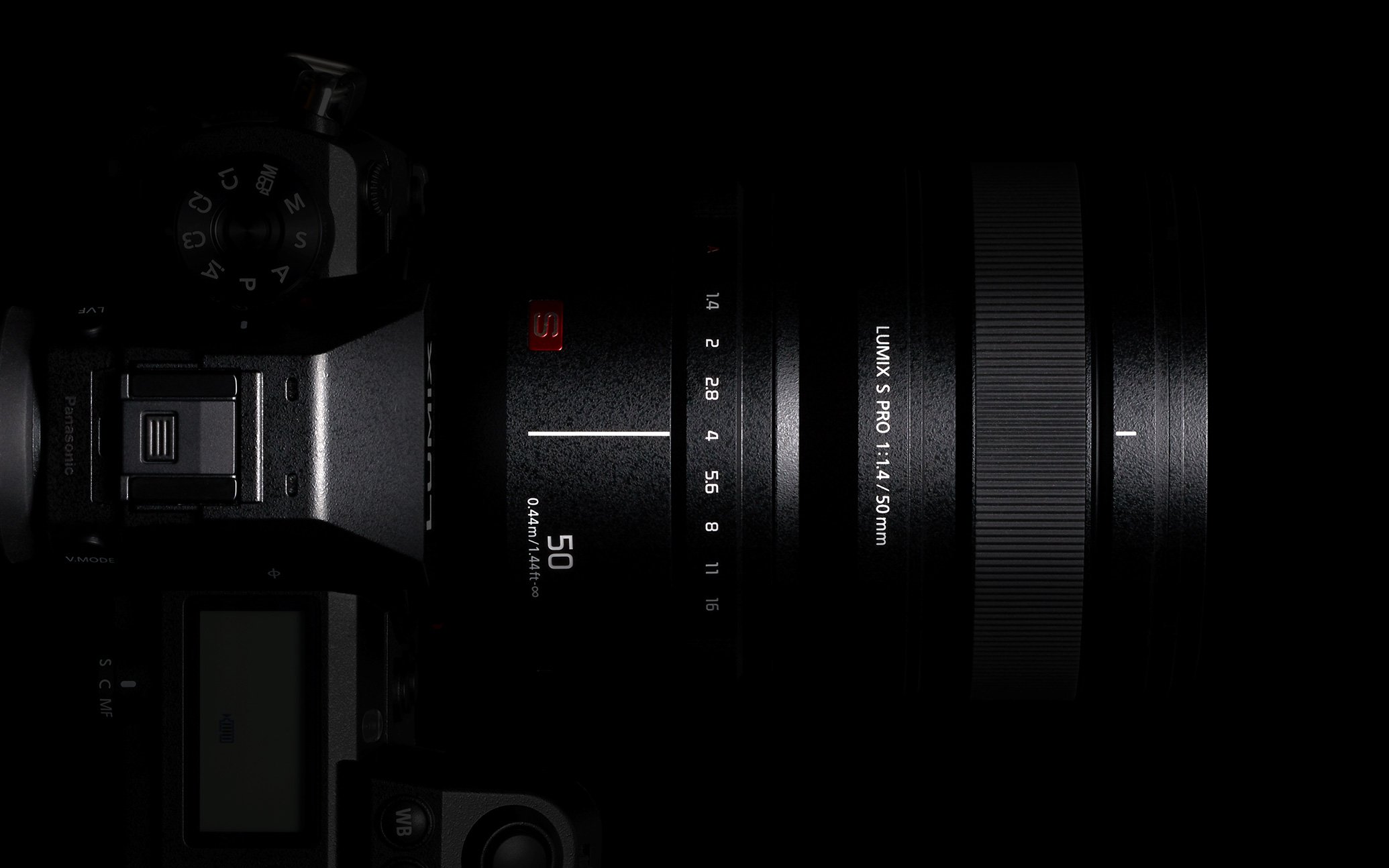 Black Panasonic LUMIX camera body with attached LUMIX S PRO 50mm F1.4 lens, partially illuminated against dark background
