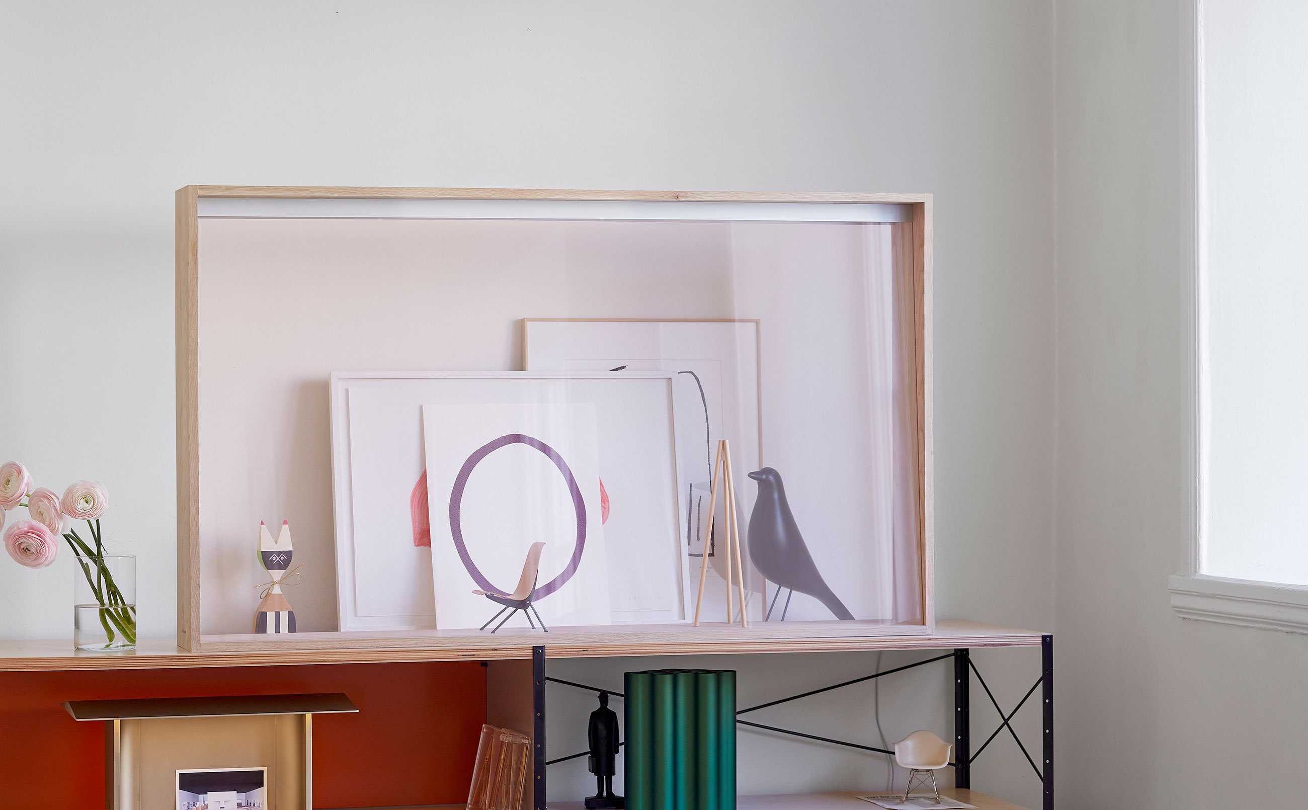 A transparent frame is placed on a shelf in a room lit by window light.