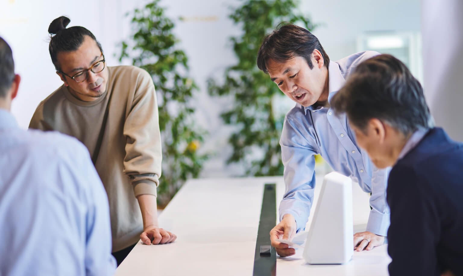 A group of four people collaborating around a table in a bright, modern office space.